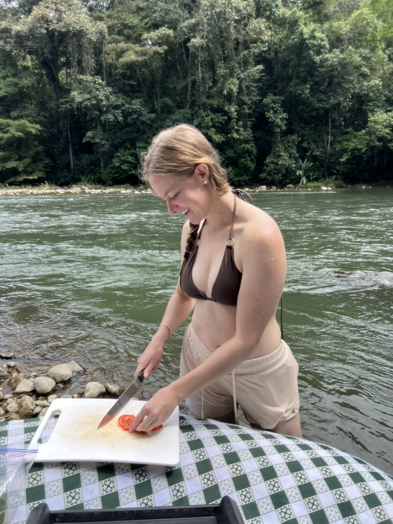 Shelby preparing food beside a river